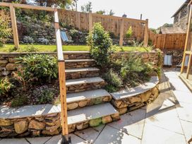 A garden with stone steps leading up to plants and a wooden fence at Haws Bank Cottage in Coniston