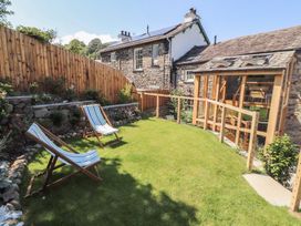 A garden with deck chairs and a wooden fence at Haws Bank Cottage in Coniston
