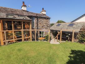 A garden with a wooden fence and stone wall at Haws Bank Cottage in Coniston