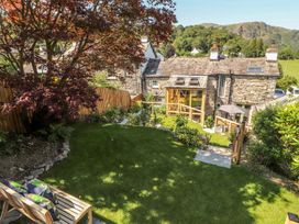 A garden with a tree and a house at Haws Bank Cottage in Coniston