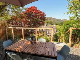 A garden with a wooden table and chairs at Haws Bank Cottage in Coniston