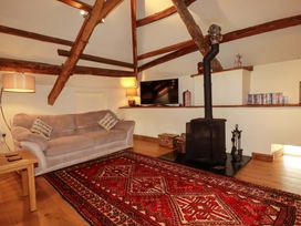 A living room with a sofa, television, and stove at The Water Mill at Boyton Mill, Launceston