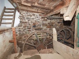 A basement with a stone wall and a water wheel at The Water Mill at Boyton Mill, Launceston