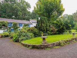 A garden with a building and trees at The Water Mill at Boyton Mill Launceston