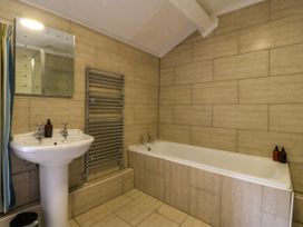A bathroom with a sink, bathtub, and mirror at Ty Mawr, Criccieth