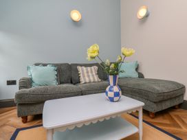 A living room with a sofa and vase of flowers at Apartment Blue in Whitby
