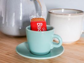 A cup with a biscuit on a saucer at Apartment Blue in Whitby