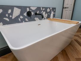 A bathtub with a wooden tray and a faucet at Apartment Blue in Whitby