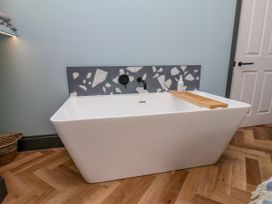 A bathroom with a bathtub and decorative wall tiles at Apartment Blue in Whitby