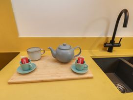 A kitchen with a teapot and cups on a cutting board at Apartment Yellow in Whitby