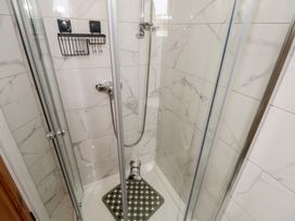 A shower with glass doors and a shower mat at Islands Inn, Louisburgh, County Mayo