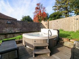 A hot tub with steps on a deck surrounded by trees at Bwthyn Bach in Pentrefelin