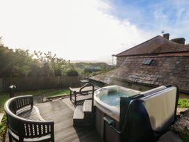 An outdoor area with a hot tub and seating at Bwthyn Bach in Pentrefelin