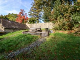 A garden with a hot tub and wooden bench at Bwthyn Bach in Pentrefelin