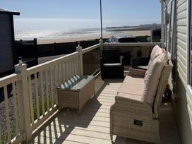 A balcony with seating and table overlooking the ocean at Trecco Bay holiday park, Porthcawl
