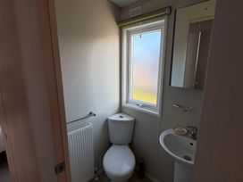 A bathroom with a toilet, sink, and window at Trecco Bay holiday park, Porthcawl