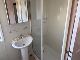 A bathroom featuring a sink, mirror, and shower cubicle at Trecco Bay holiday park, Porthcawl