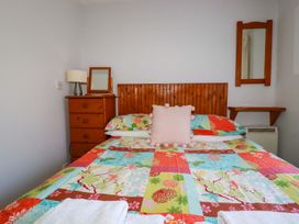 A bedroom with a bed, lamp, mirror, and chest of drawers at Chyancrowse in Penzance