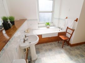A bathroom with a bathtub, sink, and chair at Chyandaunce in Penzance