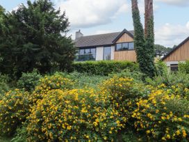 A house with windows surrounded by trees and flowers at The Barn at Bryn Eithin, Colwyn Bay