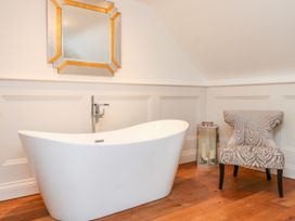 A bathroom with a bathtub and a chair at The Barn at Bryn Eithin Colwyn Bay