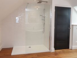 A bathroom with a shower and a door at The Barn at Bryn Eithin in Colwyn Bay