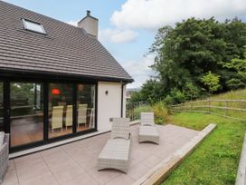 An outdoor area with patio chairs and trees at The Barn at Bryn Eithin Colwyn Bay