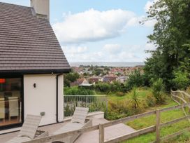 An outdoor area with a house and chairs overlooking the view at The Barn at Bryn Eithin Colwyn Bay