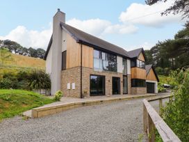 A house with a stone and wood exterior and a garage at The Barn at Bryn Eithin in Colwyn Bay