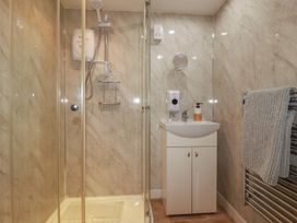 A bathroom with a shower, sink, towel rail, and soap dispenser at Moorland Retreat in Bodmin