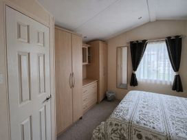 A bedroom with a bed, wardrobe, and drawers at Marine Holiday Park - 21NC Rhyl