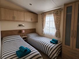 A bedroom with two beds and a wardrobe at Marine Holiday Park - 21NC Rhyl