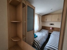 A bedroom with two beds and a nightstand at Marine Holiday Park - 21NC in Rhyl