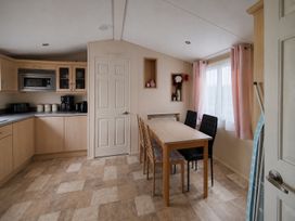 A kitchen with a dining table and chairs at Marine Holiday Park - 21NC in Rhyl