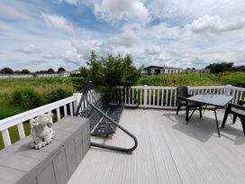 An outdoor area with decking, table, and chairs at Marine Holiday Park - 21NC Rhyl