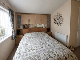 A bedroom with a bed and wardrobe at Marine Holiday Park - 21NC Rhyl