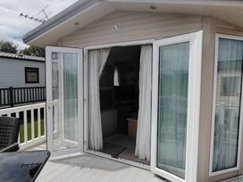 A sunroom with double doors leading outside at Marine Holiday Park - 21NC in Kinmel Bay