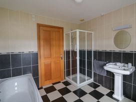 A bathroom with a bathtub, shower, sink, and door at Vernegly in Banonow