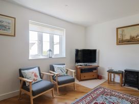 A living room with a television and two armchairs at L'Ancresse Cottage in Lyme Regis