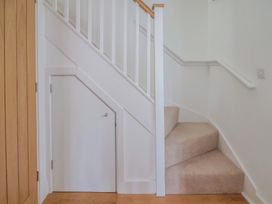 A staircase with a handrail and a door under the stairs at L'Ancresse Cottage Lyme Regis