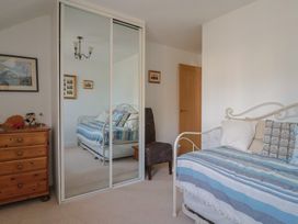 A bedroom with a bed, dresser, chair, and mirror at L'Ancresse Cottage in Lyme Regis