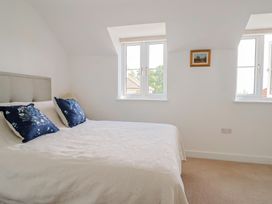 A bedroom with a bed and windows at L'Ancresse Cottage in Lyme Regis