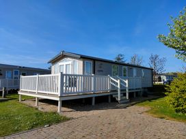 A caravan with a decking area at Primrose Valley Park - Pebbles Retreat in Primrose Valley