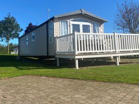 A mobile home with a deck and grass area at Primrose Valley Park - Pebbles Retreat in Primrose Valley
