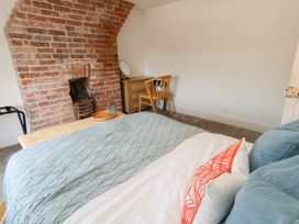 A bedroom with a bed and desk against a brick wall at The Watch House in Weymouth
