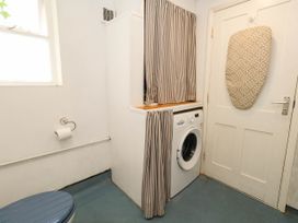 A laundry room with a toilet and washing machine at The Watch House in Weymouth