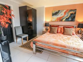 A bedroom with a bed, wardrobe, and chair at Smithy Cottage in Cemaes Bay