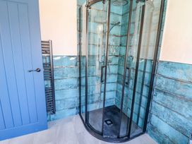 A shower with glass enclosure and towel radiator at Trefin in Cemaes Bay