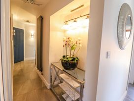 A hallway with a table and a vase of flowers at Trefin in Cemaes Bay