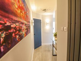 A hallway with a painting, door, and table at Trefin Cemaes Bay